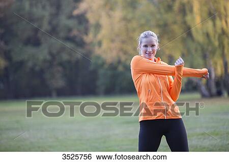 Pretty blonde woman stretching in park and smiling at camera View Large Photo Image Stock Photograph - Pretty blonde woman stretching in park and smiling at camera. Fotosearch