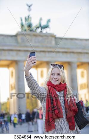 Pretty blonde woman taking a selfie in front of the Brandenburg Gate in Berlin, Germany View Large Photo Image Picture - Pretty blonde woman taking a selfie in front of the Brandenburg Gate in Berlin, Germany. Fotosearch