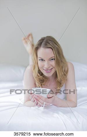 Pretty blonde woman with a cup of tea in bed smiling at camera View Large Photo Image Stock Photography - Pretty blonde woman with a cup of tea in bed smiling at camera. Fotosearch
