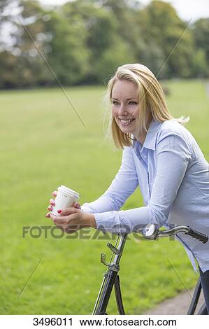 Pretty blonde woman with bicycle and coffee in park View Large Photo Image Stock Image - Pretty blonde woman with bicycle and coffee in park. Fotosearch