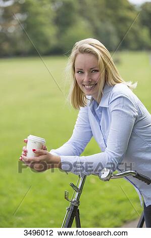 Pretty blonde woman with bicycle and coffee in park View Large Photo Image Stock Image - Pretty blonde woman with bicycle and coffee in park. Fotosearch