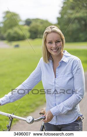Pretty blonde woman with bike in park View Large Photo Image Stock Photo - Pretty blonde woman with bike in park. Fotosearch