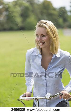 Stock Photo - Pretty blonde woman with bike in park. Fotosearch