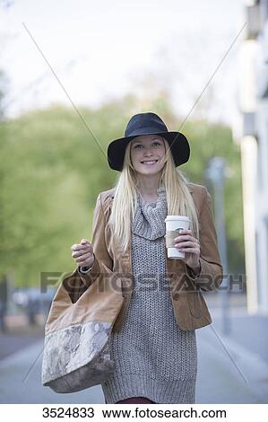 Pretty blonde woman with hat and coffee to go smiling at camera and walking in City Center View Large Photo Image Stock Image - Pretty blonde woman with hat and coffee to go smiling at camera and walking in City Center. Fotosearch