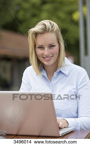 Pretty blonde woman with laptop in a Cafe smiling at camera View Large Photo Image Picture - Pretty blonde woman with laptop in a Cafe smiling at camera. Fotosearch