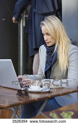 Picture - Pretty blonde woman with laptop in a Cafe. Fotosearch