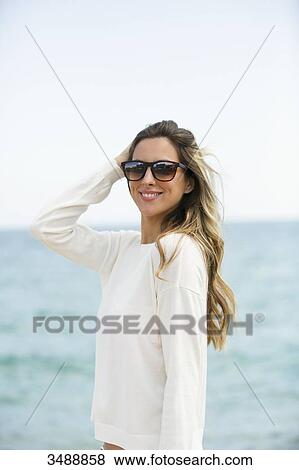 Pretty blonde woman with sunglasses at the beach smiling at camera View Large Photo Image Stock Photo - Pretty blonde woman with sunglasses at the beach smiling at camera. Fotosearch
