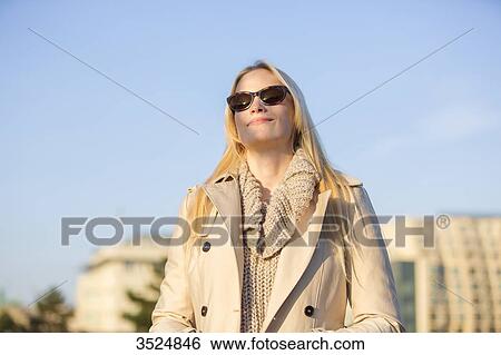 Pretty blonde woman with sunglasses enjoying the sun in a big city in Europe View Large Photo Image Stock Photograph - Pretty blonde woman with sunglasses enjoying the sun in a big city in Europe. Fotosearch