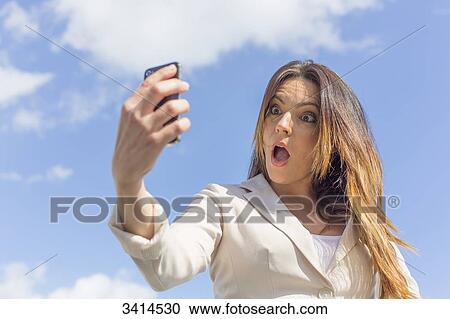 Pretty brunette woman doing a selfie with smartphone View Large Photo Image Stock Image - Pretty brunette woman doing a selfie with smartphone. Fotosearch