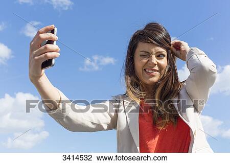 Pretty brunette woman doing a selfie with smartphone View Large Photo Image Stock Image - Pretty brunette woman doing a selfie with smartphone. Fotosearch