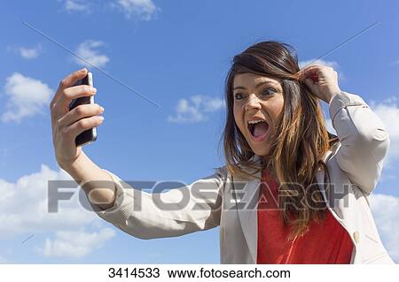 Pretty brunette woman doing a selfie with smartphone View Large Photo Image Stock Image - Pretty brunette woman doing a selfie with smartphone. Fotosearch