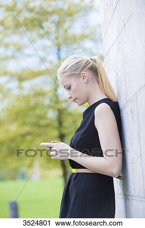 Pretty elegant woman checking her mobile in front of a office building in downtown View Large Photo Image Stock Image - Pretty elegant woman checking her mobile in front of a office building in downtown. Fotosearch
