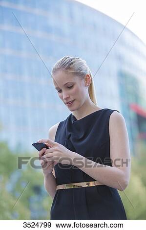 Pretty elegant woman checking her mobile in front of a office building in downtown View Large Photo Image Stock Photo - Pretty elegant woman checking her mobile in front of a office building in downtown. Fotosearch