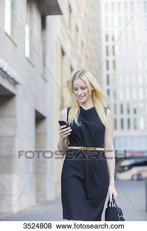 Pretty elegant woman checking her mobile in front of a office building in downtown View Large Photo Image Stock Photo - Pretty elegant woman checking her mobile in front of a office building in downtown. Fotosearch
