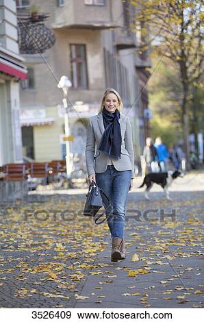 Pretty elegant woman walking with handbag in citycenter and smiling at camera View Large Photo Image Stock Photo - Pretty elegant woman walking with handbag in citycenter and smiling at camera. Fotosearch