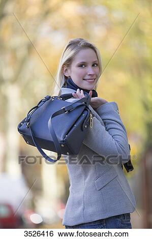 Stock Photograph - Pretty elegant woman walking with handbag in citycenter. Fotosearch