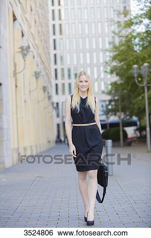 Pretty elegant woman with bag smiling at camera in downtown View Large Photo Image Stock Photograph - Pretty elegant woman with bag smiling at camera in downtown. Fotosearch