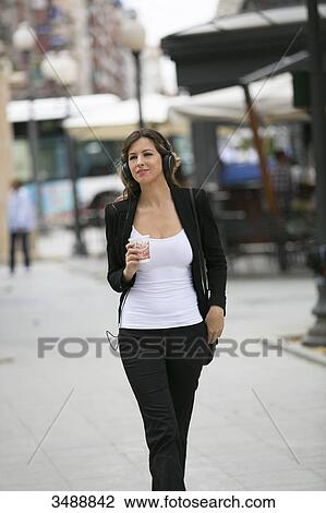 Pretty executive woman with headphones walking in downtown View Large Photo Image Stock Image - Pretty executive woman with headphones walking in downtown. Fotosearch