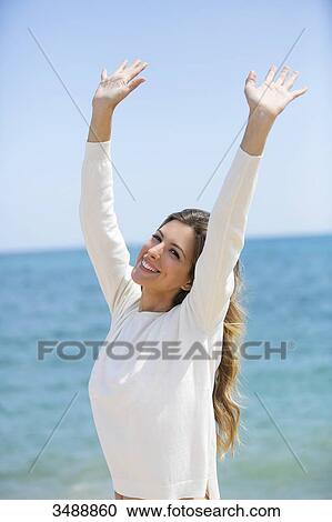 Pretty happy woman with hands-up at the beach smiling at camera View Large Photo Image Stock Image - Pretty happy woman with hands-up at the beach smiling at camera. Fotosearch
