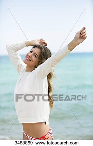 Pretty happy woman with hands-up at the beach smiling at camera View Large Photo Image Stock Photo - Pretty happy woman with hands-up at the beach smiling at camera. Fotosearch