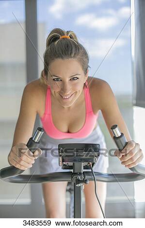 Pretty woman doing spinning bike in fitness center View Large Photo Image Stock Photo - Pretty woman doing spinning bike in fitness center. Fotosearch