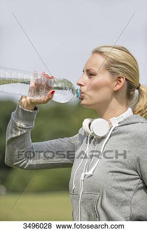 Pretty woman doing sport in park drinking water View Large Photo Image Stock Photo - Pretty woman doing sport in park drinking water. Fotosearch