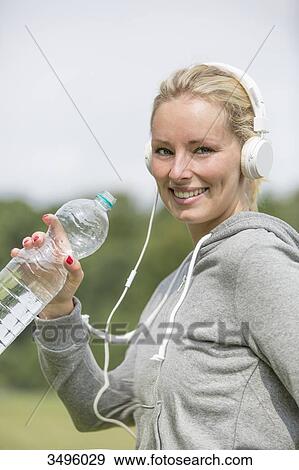 Pretty woman doing sport in park drinking water and smiling at camera View Large Photo Image Stock Photo - Pretty woman doing sport in park drinking water and smiling at camera. Fotosearch