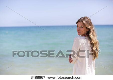 Pretty woman looking at camera at the beach View Large Photo Image Stock Photo - Pretty woman looking at camera at the beach. Fotosearch