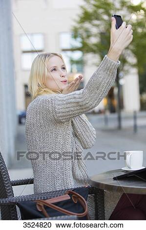 Pretty young woman doing a selfie in a Cafe in city center sending a kiss View Large Photo Image Stock Image - Pretty young woman doing a selfie in a Cafe in city center sending a kiss. Fotosearch