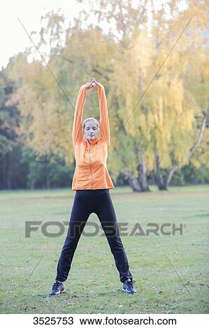 Pretty young woman stretching in park View Large Photo Image Stock Image - Pretty young woman stretching in park. Fotosearch