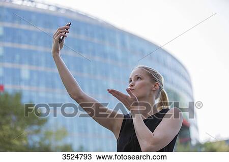 Pretty young woman taking a selfie in front of an Office Building View Large Photo Image Stock Image - Pretty young woman taking a selfie in front of an Office Building. Fotosearch