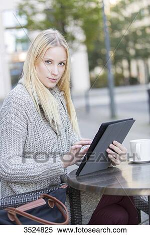 Pretty young woman with tablet in a Cafe in city center looking at camera View Large Photo Image Stock Photography - Pretty young woman with tablet in a Cafe in city center looking at camera. Fotosearch