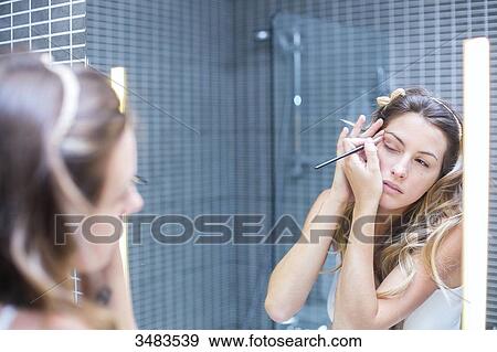 Reflection of a young woman in a mirror applying make-up View Large Photo Image Stock Photo - Reflection of a young woman in a mirror applying make-up. Fotosearch