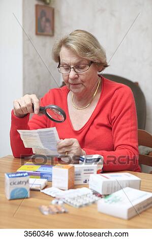 Stock Photograph - Senior woman reading medecine instructions.. Fotosearch