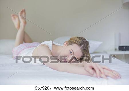 Sexy blonde woman lying in bed smiling at camera View Large Photo Image Stock Photo - Sexy blonde woman lying in bed smiling at camera. Fotosearch
