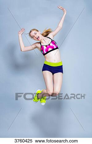 Smiling young woman dressed in fitness, front, jumps on a gray background View Large Photo Image Stock Photography - Smiling young woman dressed in fitness, front, jumps on a gray background. Fotosearch