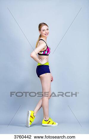 Smiling young woman in fitness attire, looking toward the lens View Large Photo Image Stock Image - Smiling young woman in fitness attire, looking toward the lens. Fotosearch