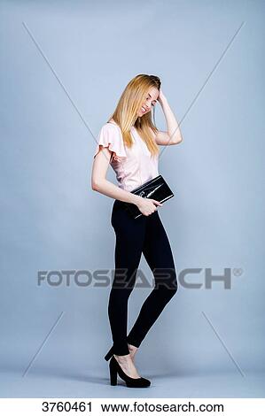Smiling young woman in the foot, one hand behind his head, staring down View Large Photo Image Stock Image - Smiling young woman in the foot, one hand behind his head, staring down. Fotosearch