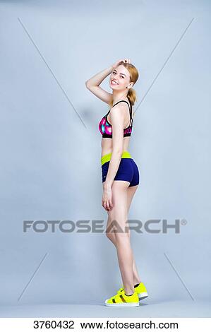 Stock Image - Smiling young woman Length, practical fitness exercises, one arm behind his head. Fotosearch