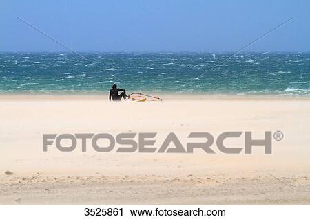 Stock Image - Spain. Andalusia, Windsurfer resting on the beach of Conil.. Fotosearch