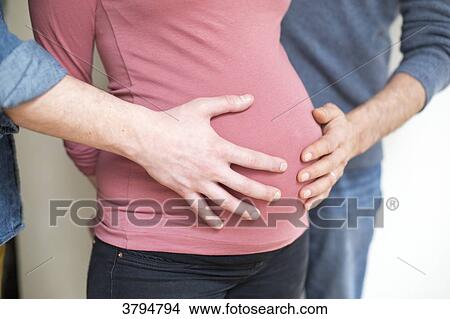 Picture - Two hands of different people on the belly of a pregnant woman.. Fotosearch
