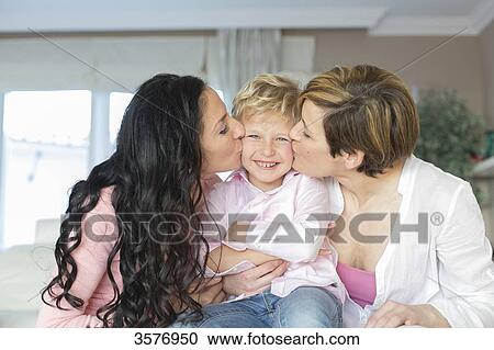Stock Image - Two women kissing a cute little boy. Fotosearch