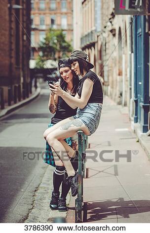 two young women captivated by a mobile phone in an urban landscape View Large Photo Image Stock Image - two young women captivated by a mobile phone in an urban landscape. Fotosearch