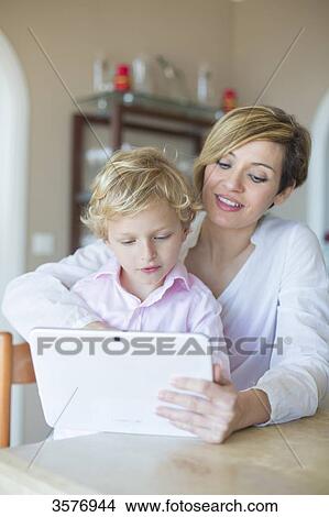 Woman and son with digital tablet at home View Large Photo Image Picture - Woman and son with digital tablet at home. Fotosearch