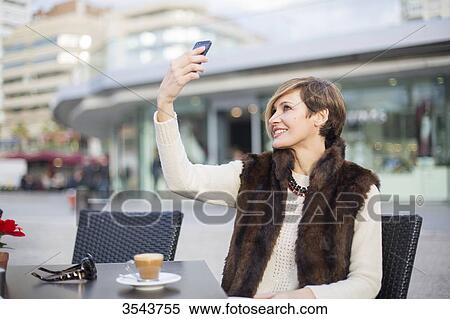 Woman doing a selfie outdoors in a Cafe View Large Photo Image Stock Photography - Woman doing a selfie outdoors in a Cafe. Fotosearch
