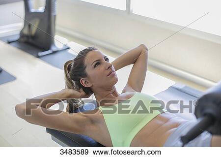 Stock Photo - Woman doing crunches in fitness center. Fotosearch