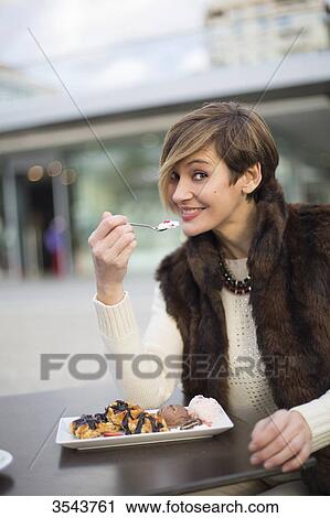 Woman enjoying a dessert and smiling at camera outdoors View Large Photo Image Stock Image - Woman enjoying a dessert and smiling at camera outdoors. Fotosearch