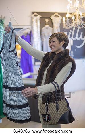 Woman holding a dress in a clothes store View Large Photo Image Stock Photography - Woman holding a dress in a clothes store. Fotosearch