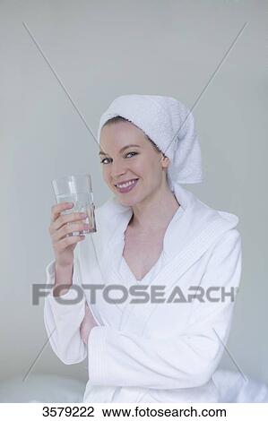 Woman in bathrobe with a glass of water smiling at camera View Large Photo Image Stock Image - Woman in bathrobe with a glass of water smiling at camera. Fotosearch