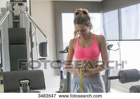 Woman in fitness center measuring her waist View Large Photo Image Stock Photo - Woman in fitness center measuring her waist. Fotosearch
